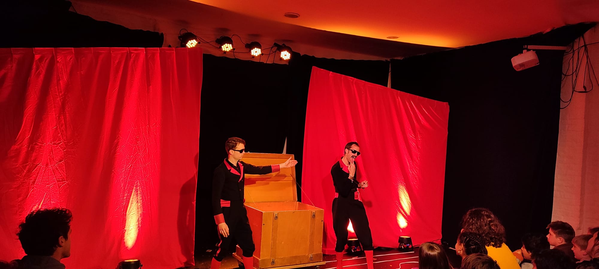 Les Demented Brothers sur scène, devant des rideaux rouges éclairés, face au public